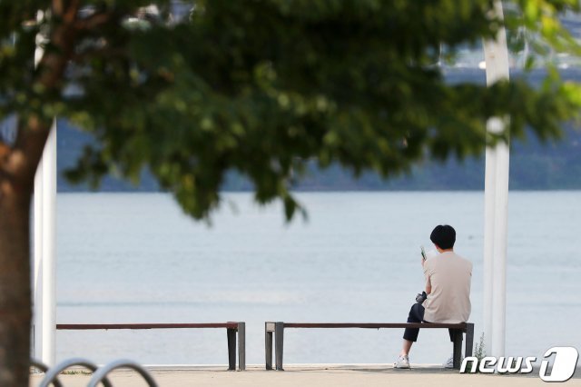 서울 지역 낮 최고기온이 35도까지 오른 22일 오후 서울 서초구 반포한강공원에서 한 시민들이 그늘을 찾아 독서를 하며 더위를 식히고 있다. 방역당국은 이날 실외에서 작업을 하고 사람 간 2m 이상 거리두기가 가능하면 마스크를 착용하지 않을 것을 권장했다. 2020.6.22 © News1