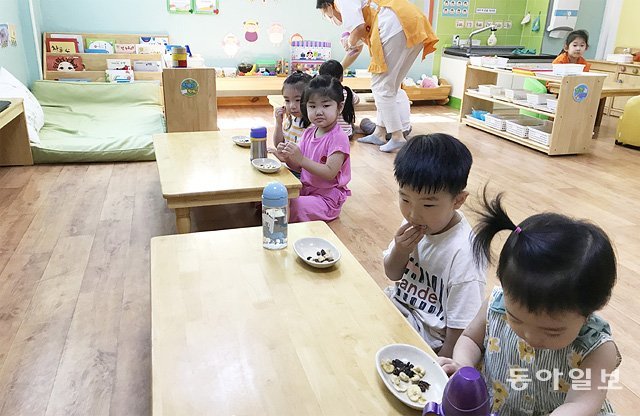 22일 대구 수성구 지산동 해달별 어린이집에서 아이들이 사회적 거리 두기 수칙에 따라 한 방향으로 앉아 간식을 먹고 있다. 명민준 기자 mmj86@donga.com