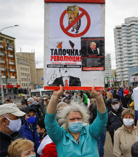 지난달 31일 벨라루스 수도 민스크에서 알렉산드르 루카셴코 대통령의 재집권을 반대하는 한 여성이 바퀴벌레에 대통령의 얼굴을 합성한 포스터를 들고 있다. 민스크=AP 뉴시스
