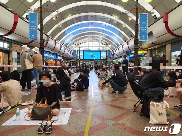 26일 오전 9시 서울 영등포구 롯데백화점 영등포점 3층 역사 광장 앞에 ‘면세 명품’을 사러 온 시민 수백명이 대기줄에 앉아 백화점 개장을 기다리고 있다.2020.6.26 © 뉴스1