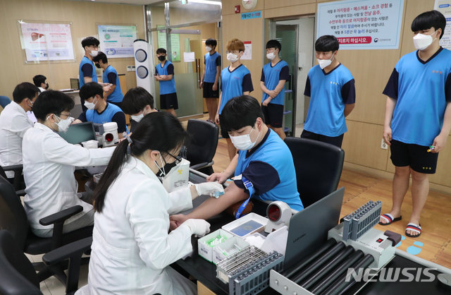 신종 코로나바이러스 감염증(코로나19) 확산 사태로 중단했던 병역판정검사가 재개된 20일 오후 인천시 미추홀구 인천병무지청에서 검사 대상자들이 사회적 거리두기를 하면서 체혈을 하고 있다. 뉴시스