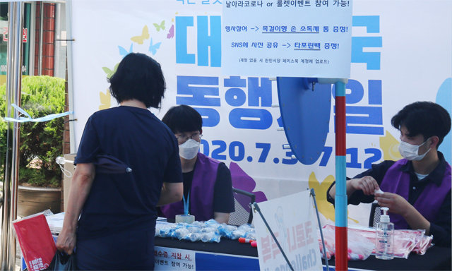 6일 대전 서구의 한민시장에서 ‘날아가라 코로나’ 이벤트에 참가한 고객이 영수증을 낸 뒤 손소독제를 받아가고 있다. 소상공인시장진흥공단 제공