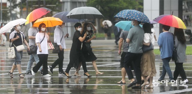 12일 비가 내린 부산 해운대구 벡스코 앞을 시민들이 우산을 쓴 채 지나가고 있다. 10일 하루에만 200mm가 넘는 비가 내렸던 부산은 13, 14일 이틀에 걸쳐 100∼200mm의 비가 더 올 것으로 예보됐다. 이번 비는 14일 오후 장마전선이 물러가면서 대부분 그칠 것으로 보인다. 부산=박경모 기자 momo@donga.com