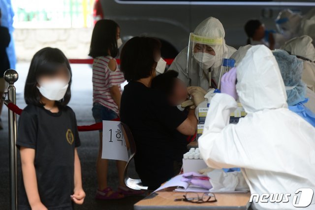 18일 오후 광주 서구 한 초등학교 이동선별진료소에서 이 학교 재학생들이 신종 코로나바이러스 감염증(코로나19) 검체를 채취하고 있다. 앞서 이날 오후 이 학교에 다니는 저학년·고학년 남매가 코로나19에 확진됐다. 2020.7.18/뉴스1 © News1