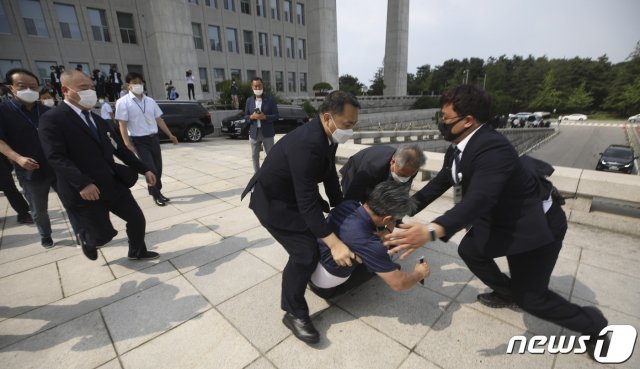 16일 오후 서울 여의도 국회에서 한 남성이 개원 연설을 마친 문재인 대통령을 향해 운동화를 집어던진 후 달려가다가 제지당하고 있다. 2020.7.16 © News1