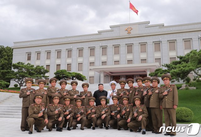 김정은 북한 국무위원장이 ‘전승절(7월 27일)’ 67주년을 맞아 군 지휘관 주요 간부들에게 ‘백두산’ 권총을 하사했다고 노동당 기관지 노동신문은 27일 전했다. 전날인 26일 수여식이 열렸던 당 중앙위원회 본부청사를 배경으로 기념사진을 찍는 김 위원장과 군 간부들의 모습.(평양 노동신문=뉴스1)