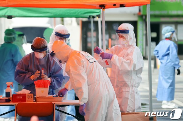 지난 16일 한 드라이브 스루(Drive Through) 선별진료소에서 구청 보건소 직원들이 차량에 탄 시민과 아이들의 검체를 채취하고 있다. © News1