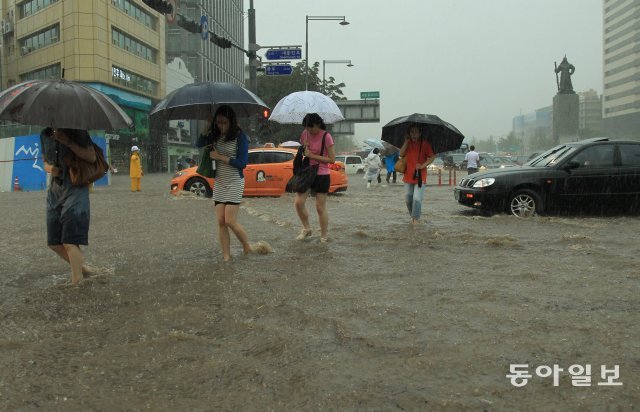 지난 11년 7월 서울 광화문 사거리에서 시민들이 집중호우에 불어난 물을 헤치며 걸어가고 있다. 동아DB