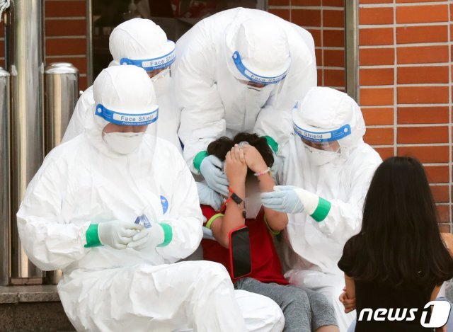 서울 중랑구의 한 초등학교에 마련된 선별진료소에서 지난 5일 의료진들이 진단검사를 받는 학생을 위로하고 있다./뉴스1 © News1