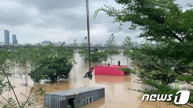 서울 지역에 집중호우가 내린 3일 오후 서초구 한강시민공원 잠원지구에서 컨테이너 이동 작업 중이던 인부 2명이 불어난 물에 고립돼 소방대원들이 구조하고 있다.(서초소방서 제공) 2020.8.3/뉴스1