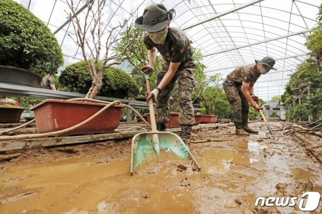며칠간 중부지방에 폭우가 이어진 5일 오후 경기도 안성시 일죽면의 한 농원에서 육군 지상작전사령부 예하 55사단 장병들이 밀려온 토사를 정리하며 수해 복구 작업을 하고 있다. 2020.8.5 © News1