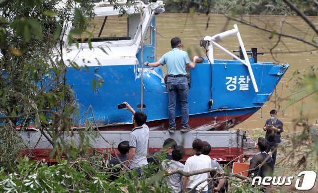 의암댐 선박 전복 사고 발생 사흘째인 8일 실종자 가족들이 강원도 춘천시 남산면 서천리 경강대교 상류 1.6km 지점에서 인양된 경찰정을 바라보고 있다. 지난 6일 강원 춘천시 의암댐 인근에서 수초 섬을 고정 작업하던 민간 고무보트와 춘천시청 행정선(환경감시선), 경찰정 등 선박 3척이 전복돼 5명이 실종된 상황이다. 2020.8.8/뉴스1 © News1