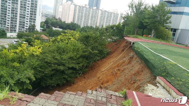 지반이 무너지면서 보도블록과 토사가 10m 아래로 떠내려간 모습.(부산경찰청 제공)