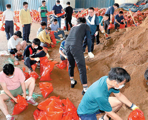 모래주머니라도… 광주 광산구 직원들이 9일 광산구 송정동 송정나들목 공영차고지에서 호우로 무너진 제방을 복구하기 위해 방수용 모래주머니를 만들고 있다. 광주=뉴스1