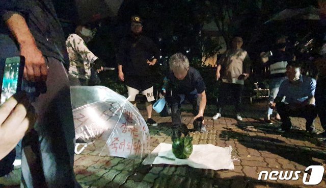 문재인 대통령을 향해 신발을 벗어 던진 뮤지컬 극단 ‘긍정의 힘’ 정창옥 단장(57)이 19일 오후 법원의 영장이 기각되면서 서울 영등포경찰서 유치장을 나와 신발로 수박을 깨는 퍼포먼스를 하고 있다. 2020.7.19/뉴스1 © News1