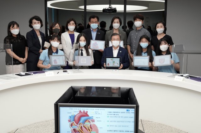 문재인 대통령이 18일 오전 ‘한국판 뉴딜, 현장에 가다’의 일환으로 그린 스마트 교육을 시행 중인 서울 중구 창덕여자중학교를 방문해 스마트 수업 시연 참여 후 태블릿PC를 들고 학생 및 관계자 등과 기념촬영을 하고 있다. 사진=청와대 제공