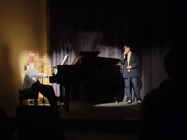 허영희 교수가 함께 탈북한 제자의 피아노 연주에 맞춰 한 공연에 참가해 노래를 부르고 있다.