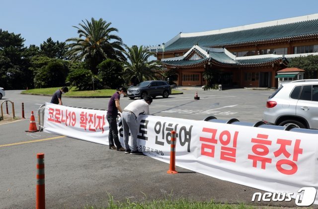 21일 제주 서귀포시 중문관광단지내 중문골프장에서 ‘신종 코로나바이러스감염증’(코로나19) 확진자가 나와 직원들이 휴장 안내 현수막을 달고 있다. 뉴스1