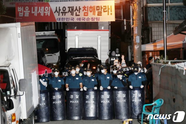 21일 오후 서울 성북구 사랑제일교회 압수수색에 나선 경찰이 방역복 차림으로 좁은 진입로를 통해 교회로 향하고 있다. 경찰은 교인 명단을 비롯해 광복절 집회 참석자 명단 등을 집중적으로 확보할 예정이다. 2020.8.21 © News1