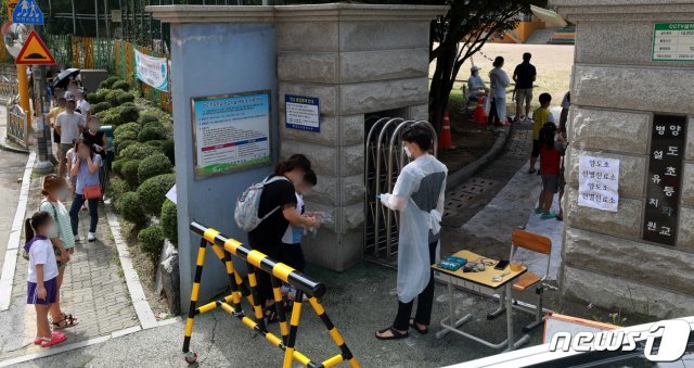 방역당국은 23일 김포 양도초등학교에 선별진료소를 설치하고 2~3학년과 교직원 158명에 대한 검체 검사를 진행한다. 사진은 이날 학무모와 아이들이 검사를 받기 위해 줄지어 서 있는 모습. 2020.8.23/뉴스1