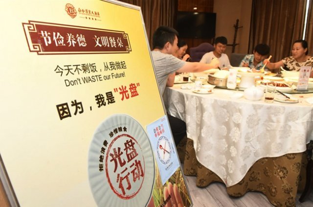 중국의 한 식당에서 손님들이 잔반줄이기 표지판 옆에서 식사하고 있다. [CNA]