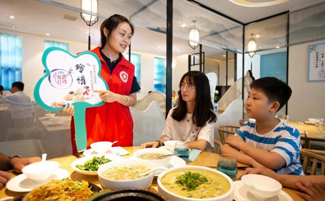 중국의 한 식당에서 종업원이 손님들에게 잔반 줄이기 운동을 설명하고 있다. [VCG]