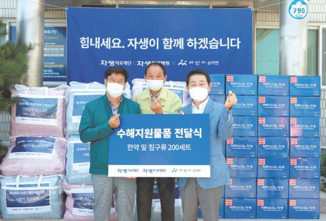 생의료재단 박병모 이사장(오른쪽)과 신민식 사회공헌위원장(왼쪽)이 수해지원물품 전달식에서 한약과 침구류 기부 후 송악면 김영진 면장과 사진 촬영을 하고있다. 자생의료재단 제공