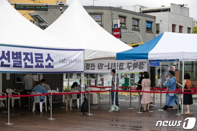 서울 성북구 성북구청 앞에 마련된 코로나19 선별진료소를 찾은 시민들이 검사를 위해 줄 서 있다./뉴스1 © News1