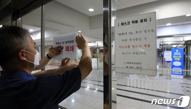 27일 새벽 서울 여의도 국회의사당에서 관계자가 본청 폐쇄를 알리는 안내문을 붙이고 있다. 전날 국회를 취재하던 한 언론사 기자가 신종 코로나바이러스 감염증(코로나19) 확진 판정을 받으면서 경내 일부 건물이 27일 하루동안 폐쇄된다. 2020.8.27/뉴스1 © News1