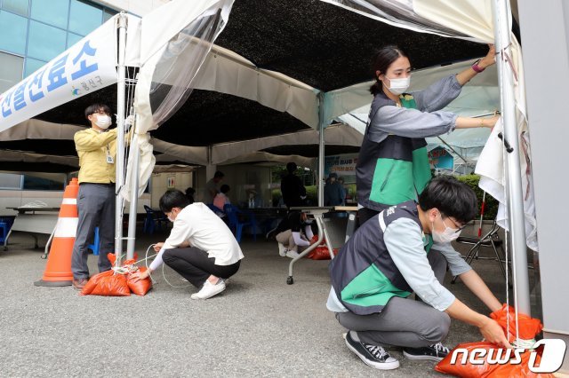 태풍 ‘바비(BAVI)’가 북상 중인 26일 오전 광주 광산구청 직원들이 신종 코로나바이러스 감염증(코로나19) 선별진료소에서 천막이 바람에 날아가지 않도록 모래주머니로 고정시키고 있다.(광주 광산구 제공) 2020.8.26/뉴스1