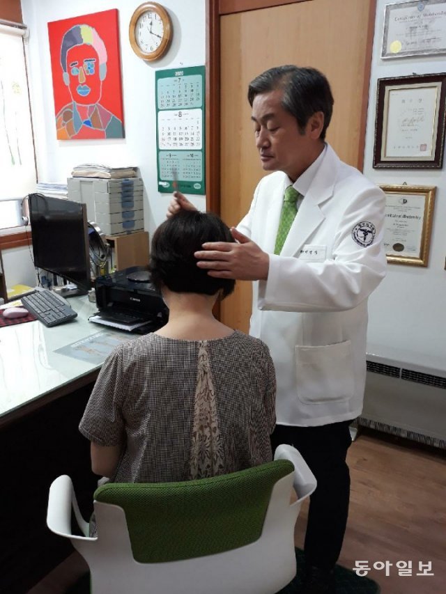 백명기 원장(오른쪽)이 환자의 머리를 살펴보고 있다. 백 원장은 15년전 탈모로 자살을 고민하던 친구 딸을 치료한 뒤 탈모치료 전문가가 됐다.