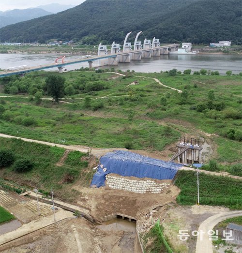 지난달 9일 폭우 때 붕괴됐던 경남 창녕의 합천창녕보 상류 제방이 복구돼 지난주 파란색 비닐막이 덮여 있다. 멀리 보이는 다리가 낙동강을 가로지르는 공도교다. 다리 아래 일부 구간에 보가 설치돼 있다. 제방 붕괴 때는 강의 둔치까지 모두 물에 잠겼었다. 제방 아래에 3개의 배수구가 보이는데 배수구와 제방 사이로 물이 스며든 것이 제방 붕괴의 원인이 됐다는 진단이 나오고 있다. 창녕=양회성 기자 yohan@donga.com