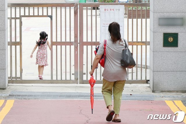 1서울의 한 초등학교에서 지난 16일 한 어머니가 자녀를 오후 돌봄교실에 바래다주고 있다./뉴스1 © News1