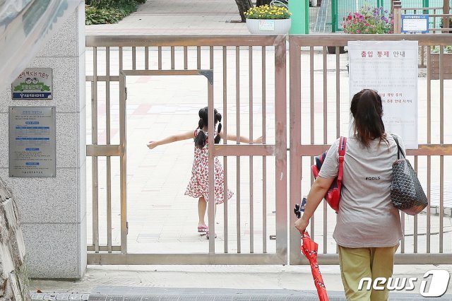 서울 한 초등학교에서 지난 16일 어머니가 자녀를 오후 돌봄교실에 바래다주고 있다. /뉴스1 © News1
