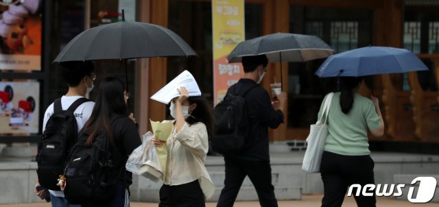 빗방울이 떨어지자 우산을 챙기지 못한 시민이 인쇄물로 비를 막으며 발걸음을 재촉하고 있다. (자료사진) © News1