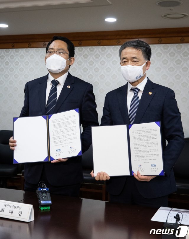 박능후 보건복지부 장관(오른쪽)과 최대집 대한의사협회장이 지난 4일 서울 종로구 정부서울청사에서 집단휴진을 중단하고 의대정원 확대 등의 의료정책을 협의하는 의정협의체를 구성하는 내용의 합의문에 서명한 후 합의문을 들고 포즈를 취하고 있다. 2020.9.4/뉴스1 © News1