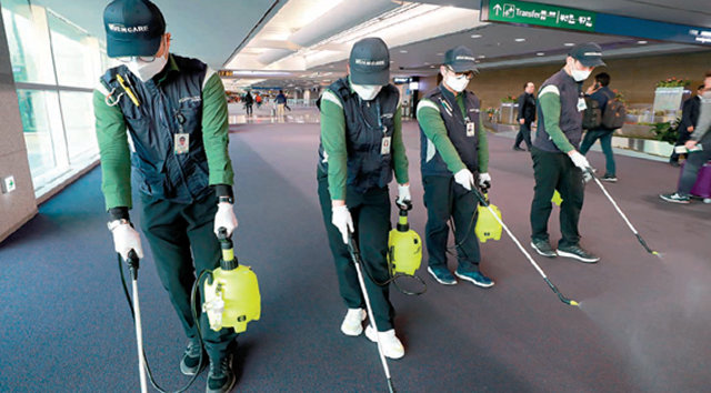 인천국제공항 제1여객터미널 입국장 통로에서 방역 담당 직원들이 바닥에 깔린 카펫을 소독하고 있다. 인천국제공항공사 제공