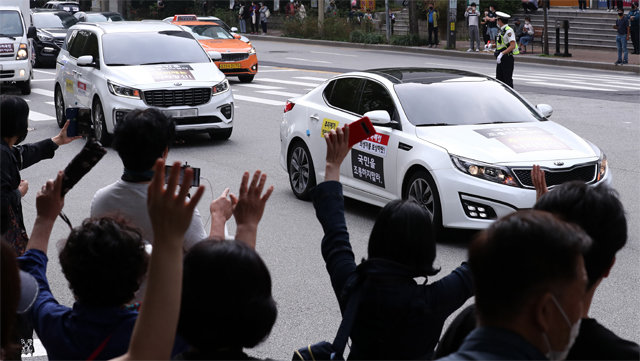 3일 오후 차량을 이용해 ‘드라이브스루’ 집회를 연 보수단체 애국순찰팀이 서울 광진구에 있는 추미애 법무부 장관 자택 인근을 지나며 경적을 울리자 몇몇 시민이 손을 흔들며 환호하고 있다. 뉴시스