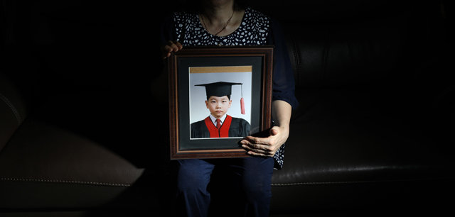 어머니 윤모 씨가 스물다섯 살에 증발해버린 아들 홍민석 씨의 유치원 졸업사진을 들고 있다. 윤 씨는 “언론을 통해서라도 아들을 찾고 싶다”며 아들의 실명을 공개해도 된다고 취재팀에 밝혔다.