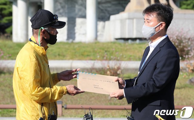 북한 피격 사망 공무원 A씨의 형 이래진씨가 8일 서울 청와대 분수대 앞에서 청와대 시민사회수석 비서관실 행정관에게 A씨의 아들이 작성한 원본 편지를 전달하고 있다. 2020.10.8/뉴스1 © News1