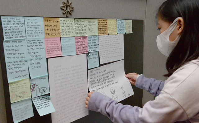 울산 삼환아르누보 주상복합아파트 화재로 집에서 대피해 임시 숙소에서 머물고 있는 한 어린이가 11일 소방관과 경찰관에게 쓴 감사 편지를 게시판에 붙이고 있다. 울산=뉴시스