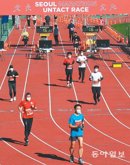 25일 서울 잠실종합운동장에서 열린 ‘2020 서울마라톤 언택트 레이스 오프라인 대회’에서 마스터스 마라토너들이 트랙을 달리고 있다. 사회적 거리 두기 방역 수칙을 지키기 위해 조별로 시간대를 달리해 출발한 참가자들은 마스크를 쓴 채 올림픽주경기장과 보조경기장을 10바퀴(10km) 돌았다. 신체 접촉을 방지하기 위해 정해진 3개 레인(1, 4, 7번)
에서만 뛰었고, 추월할 때는 바로 옆 레인(2, 5, 8번)을 사용했다. 김동주 기자 zoo@donga.com