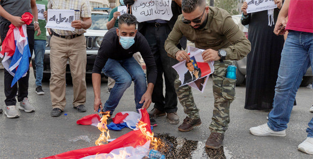 27일 팔레스타인 서안 도시 라말라에서 시위대가 프랑스 국기와 에마뉘엘 마크롱 대통령의 사진을 불태우고 있다. 라말라=AP 뉴시스