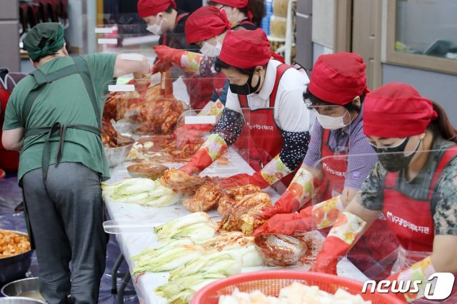 지난9월23일 대구시 남구종합사회복지관에서 열린 ‘추석맞이 김장 나눔 한마당’ 행사에 참석한 자원봉사자들이 신종 코로나바이러스 감염증(코로나19) 예방을 위해 투명 칸막이를 설치해 놓고 어려운 이웃에게 전달할 김장 김치를 버무리고 있다.  2020.9.23/뉴스1 © News1