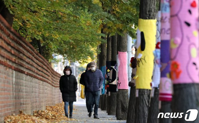 올가을 들어 가장 추운 날씨를 보인 4일 오후 경기도 광명시내 한 거리에서 두꺼운 외투를 입은 시민들이 뜨개옷을 입은 가로수 옆을 걷고 있다. 2020.11.4 © News1