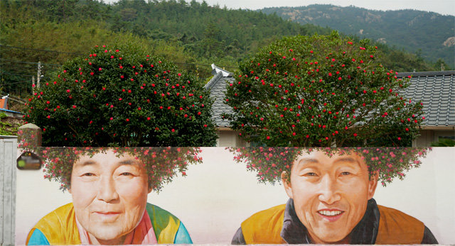 신안 암태도의 기동마을 삼거리 담벼락에 그려진 마을 주민 노부부의 동백꽃 파마머리 벽화가 눈에 띈다.