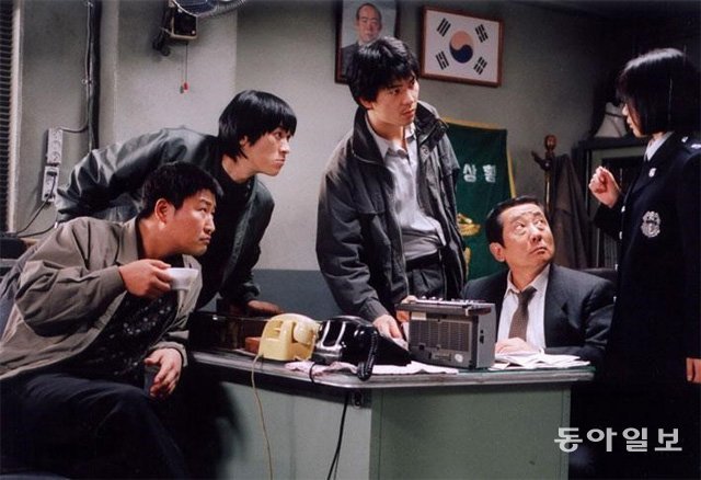 영화 ‘살인의 추억’(2003년)에서 고 송재호 배우가 분한 신동철 형사반장(오른쪽에서 두 번째)이 여경의 추리에 귀를 기울이고 있다. 동아일보DB