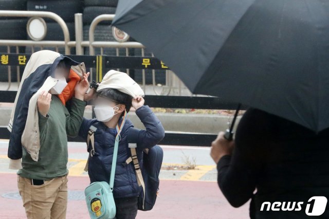 17일 오후 경기도 오산시내에서 초등학생들이 소나기가 내리자 옷과 가방을 머리에 쓴 채 비를 피하고 있다. 2020.11.17 © News1