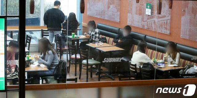 18일 오후 서울 용산구의 한 쇼핑몰 내 패스트푸드점에 시민들이 거리를 유지한 채 식사를 하고 있다. 전국의 신종 코로나바이러스 감염증(코로나19) 확진자가 이날 300명대를 기록하면서 정부는 오는 19일 0시를 기해 수도권 지역 사회적 거리두기 단계를 1단계에서 1.5단계로 격상하기로 했다. 2020.11.18 © News1