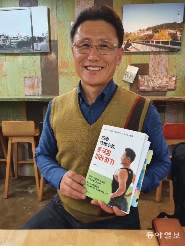 문용휴 매니저가 자신이 쓴 책 ‘건강한 100세 인생, 문 국장 따라하기’를 들고 활짝 웃고 앴다. 양종구 기자 yjongk@donga.com